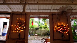 A covered outdoor area with a fan, decorative lights, and potted plants. - Patty's Secret Garden (Ko Lanta)