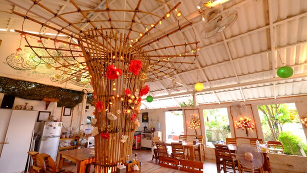 A restaurant with a bamboo ceiling structure, wooden furniture, and a visible toilet sign. - Patty's Secret Garden (Ko Lanta)