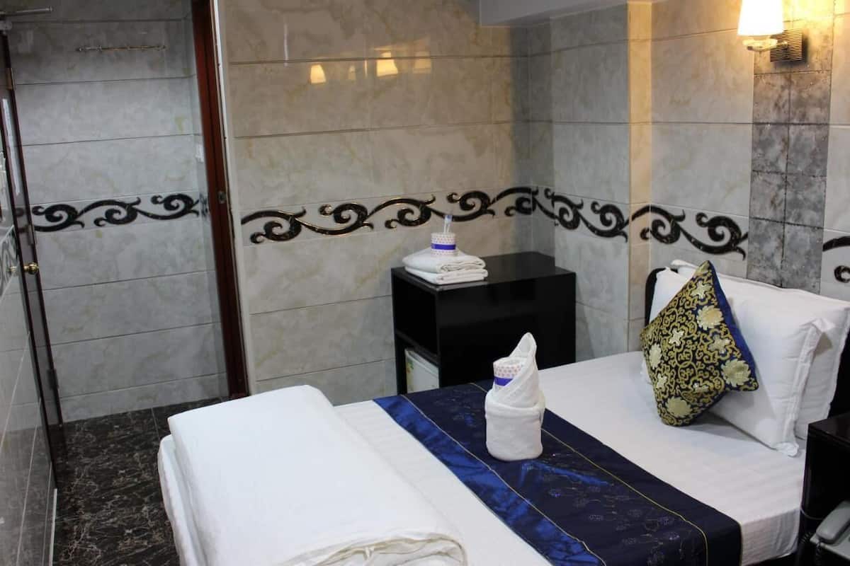 A hotel room with a bed, a nightstand, and a bathroom with a shower.