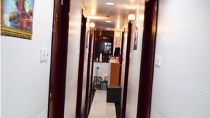 A hotel hallway with a polished floor, wooden doors, and a reception desk in the distance. - Om Guest House (Kowloon)
