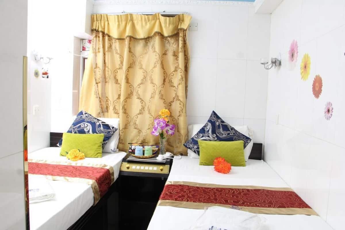 A hotel room with two beds, each with a red and white patterned bedspread, and a small table between them.