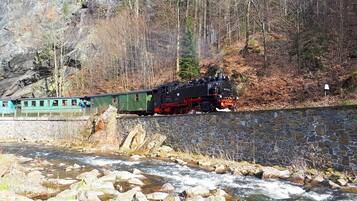 Een trein rijdt door een rotsachtig gebied met een rivier op de voorgrond.