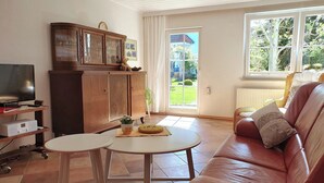 Una sala de estar con un sofá de cuero, un mueble de madera con puertas de vidrio, un televisor y una pequeña mesa con una planta.