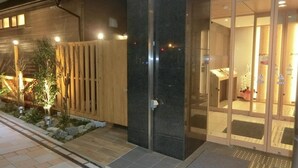 A modern building with a wooden fence, a dark pillar, and a glass door entrance. - Super Hotel Miyazaki (Miyazaki)