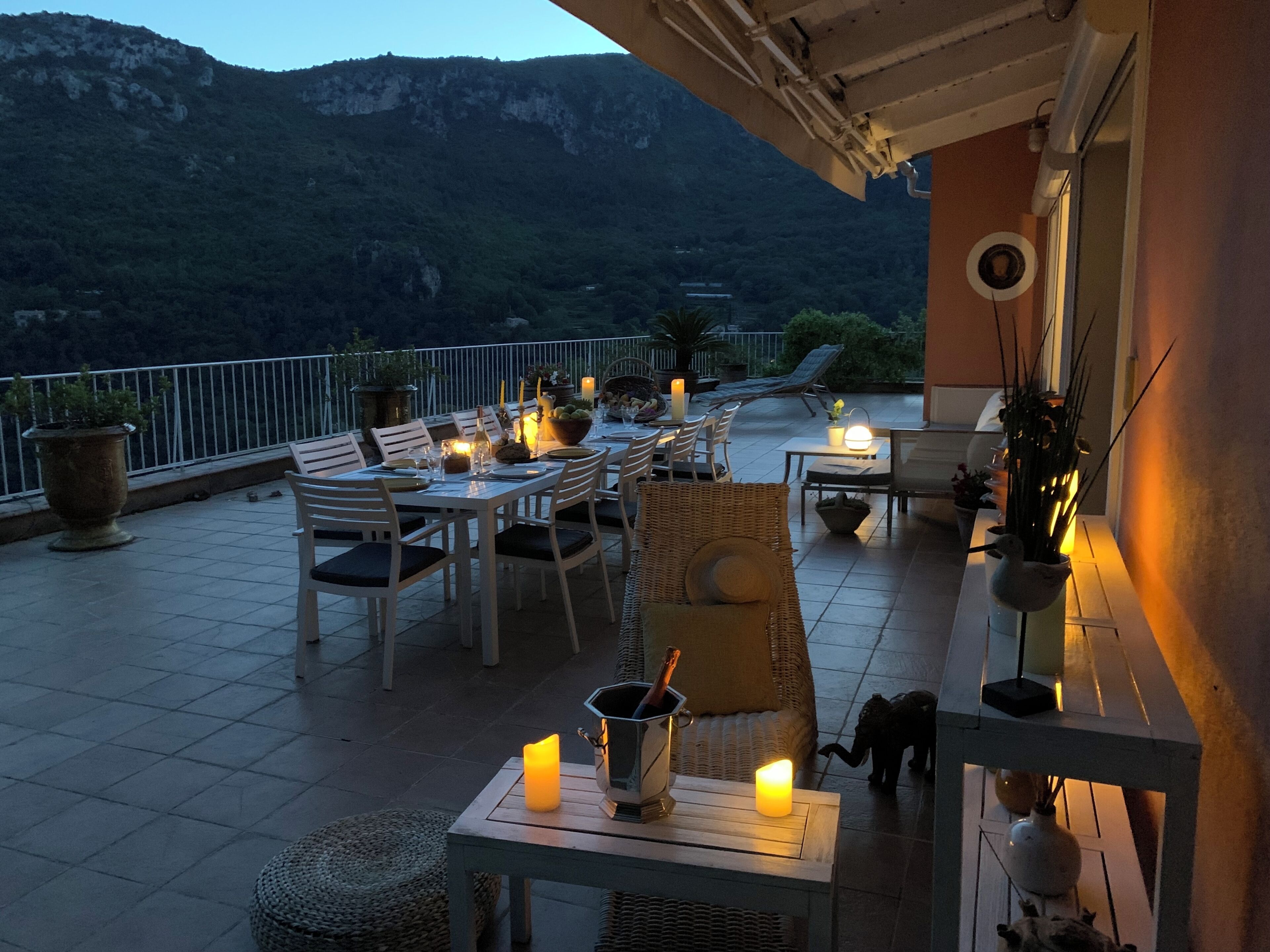 An outdoor dining area with tables and chairs, candles, and potted plants.