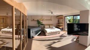 Een moderne hotelkamer met twee bedden, een grote televisie en uitzicht op het omliggende landschap.