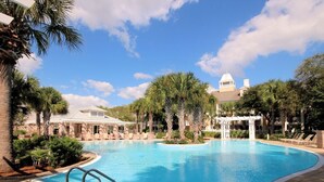 A swimming pool with palm trees, lounge chairs, and a building with a dome in the background. - Beautiful views overlooking the pool & hot tub (Miramar Beach)