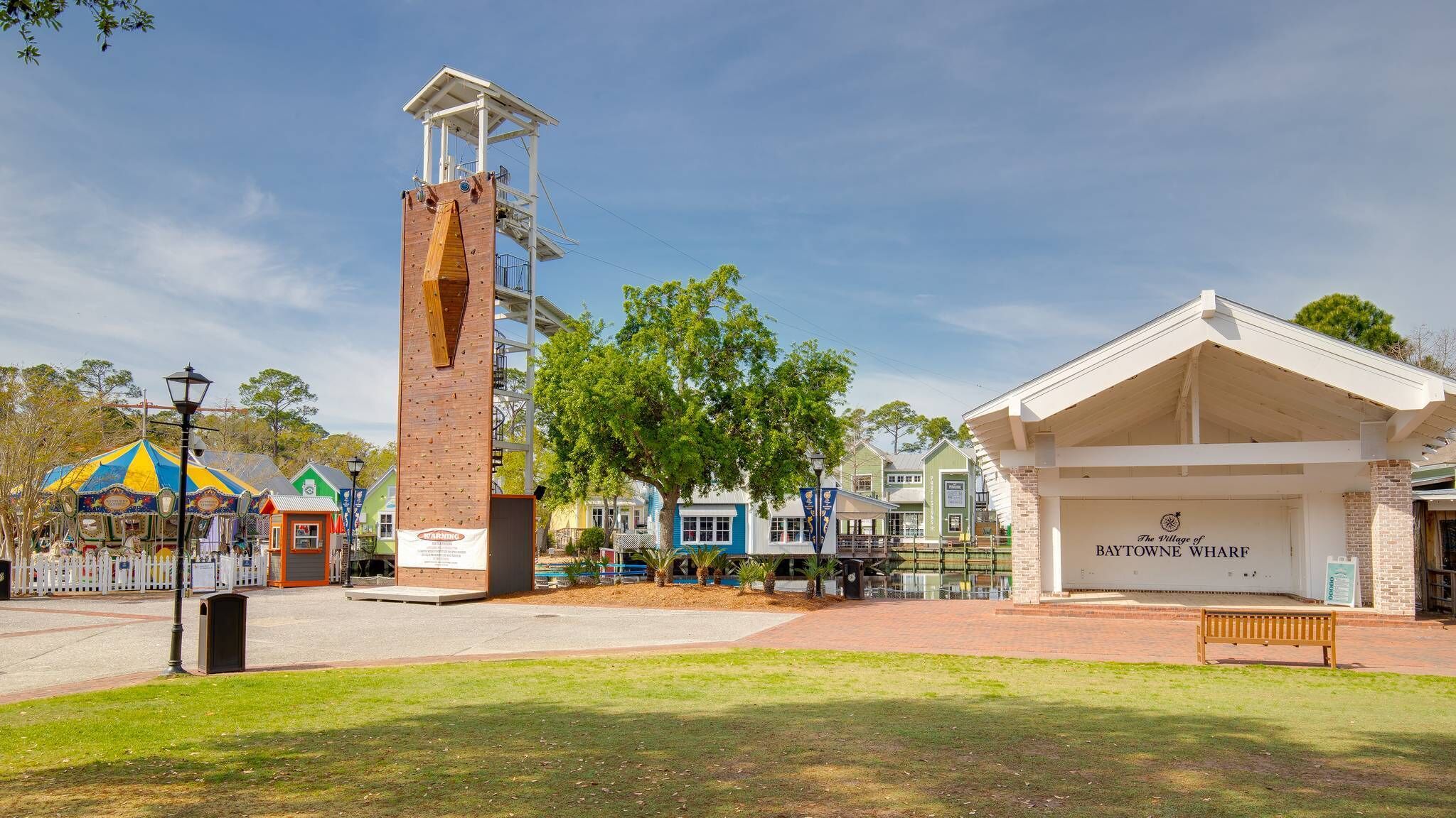 A historic building with a clock tower, a covered porch, and a sign reading 'The Village of Baytown Wharf.'