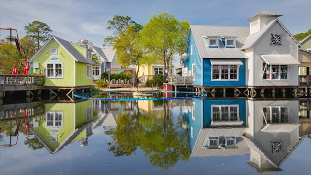 A waterfront property with multiple buildings, a dock, and a calm reflective water surface. - Beautiful views overlooking the pool & hot tub (Miramar Beach)