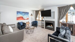 A living room with a fireplace, a sofa, a chair, a coffee table, and a flat-screen TV. - Beautiful park like setting- Telluride Lodge Condo  (Telluride)