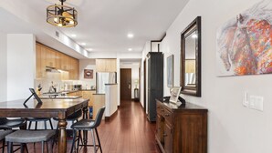 A modern kitchen with wooden cabinets, a central island with bar stools, and a dining table.