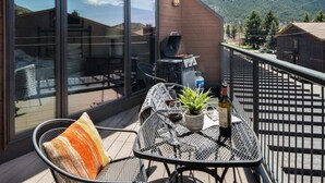 A balcony with a grill, outdoor seating, and a view of a mountain.