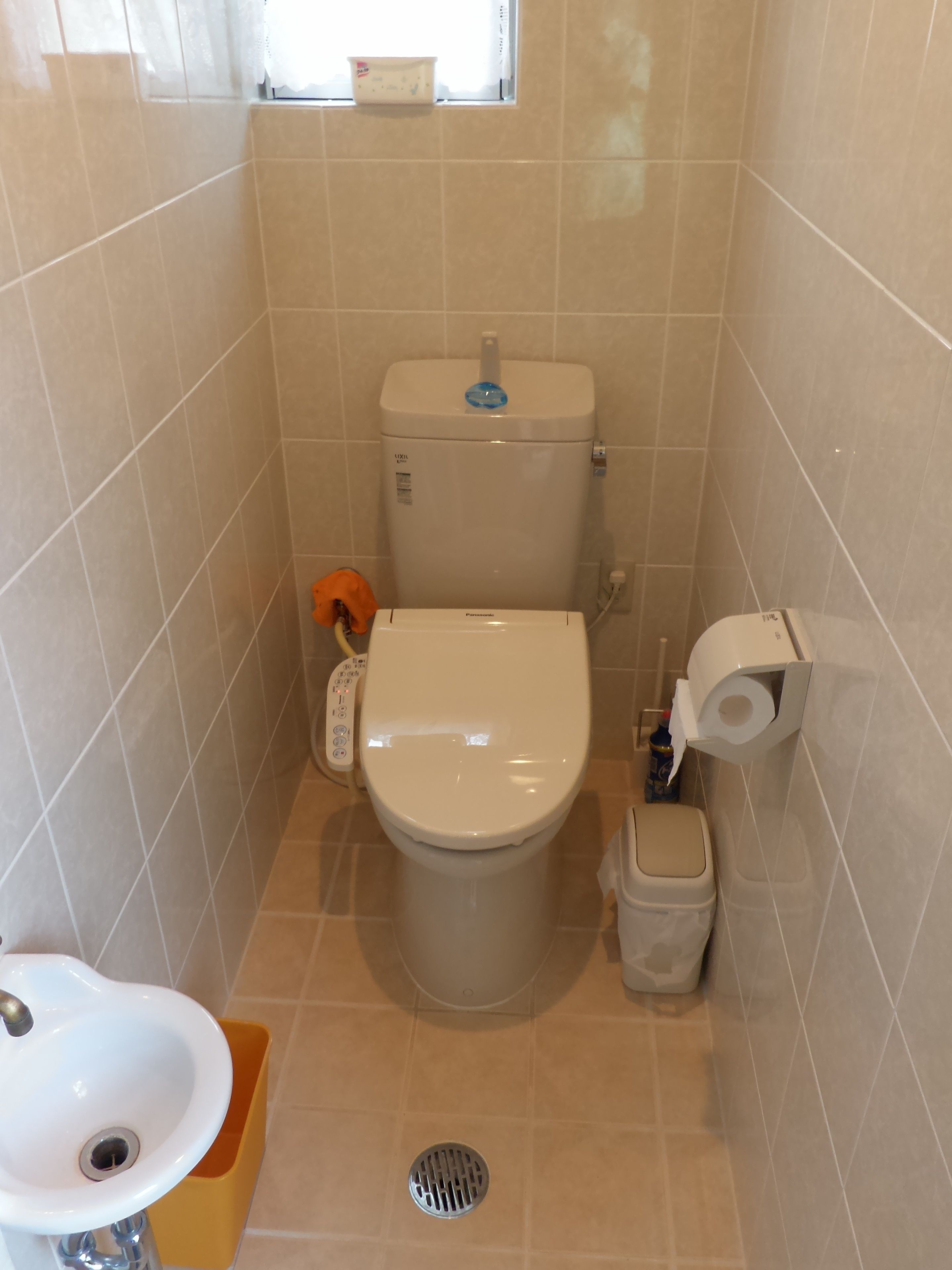 A small bathroom with a toilet, sink, and a window.