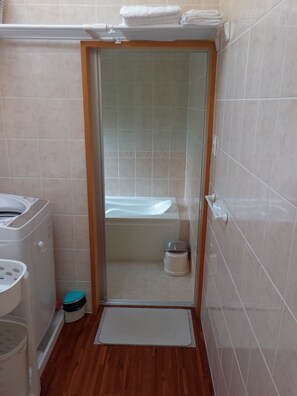 A small bathroom with a toilet, sink, and bathtub. - Kaeruya (Nakijin)
