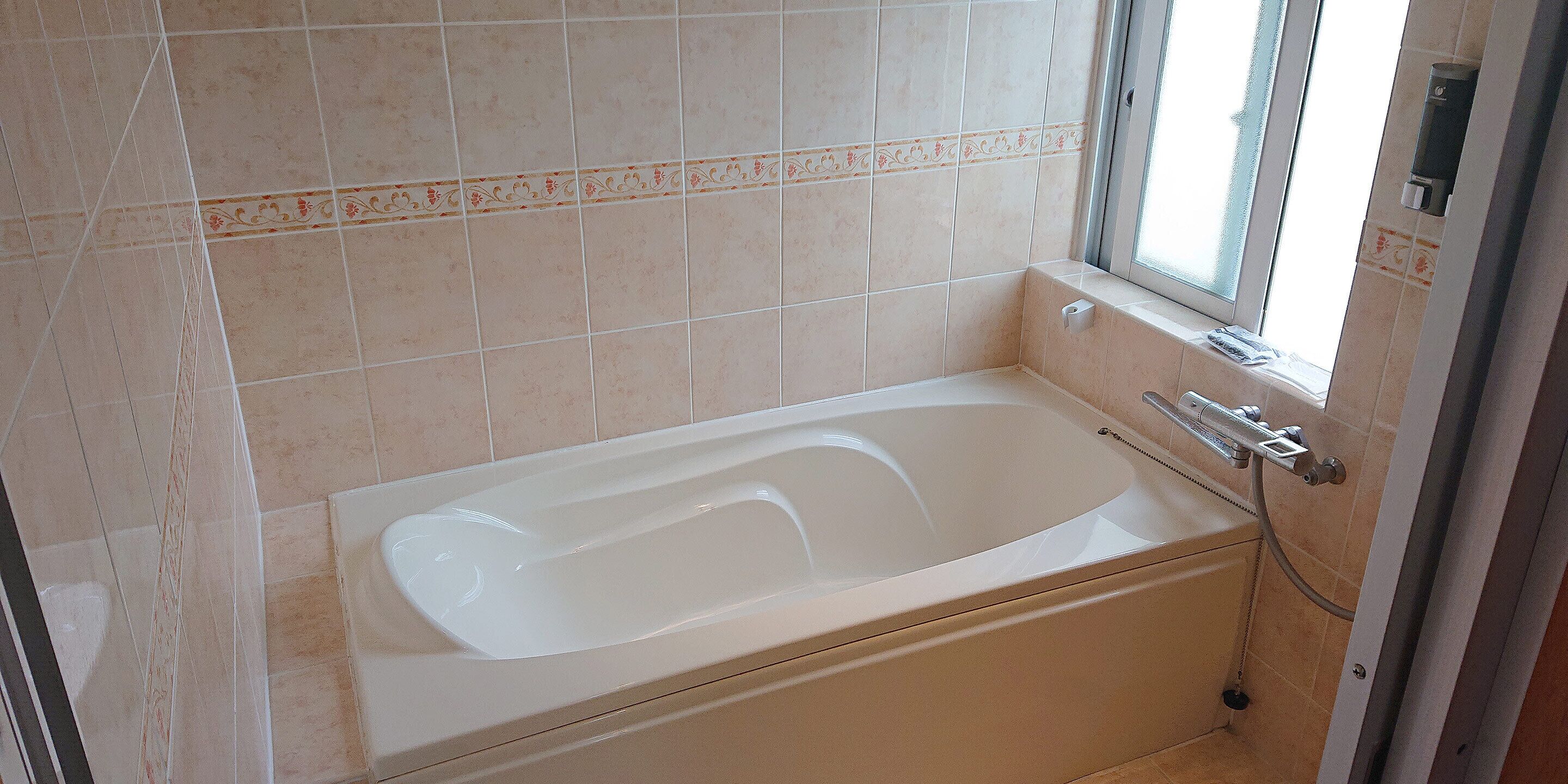 A bathroom with a bathtub, a window, and a shower.