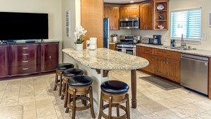 A modern kitchen with granite countertops, stainless steel appliances, wooden cabinets, and a bar stool area. - Prime Beachside Stay – Unbeatable Location #8 (Carlsbad)