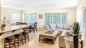 A spacious living area with a dining table, bar stools, a sofa, and a coffee table. - Prime Beachside Stay – Unbeatable Location #8 (Carlsbad)