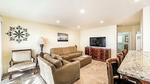 A living room with a sofa, armchair, dining table, and TV. - Relax & Unwind at Beach Rental 2 (Carlsbad)