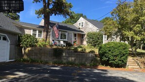 A two-story house with a garage, a front yard with a small bush, and an American flag.