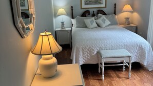 A bedroom with a bed, bedside lamps, a mirror, a bench, and a cabinet.