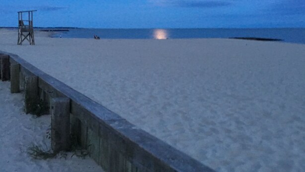 A beach with a wooden walkway and a lifeguard tower.