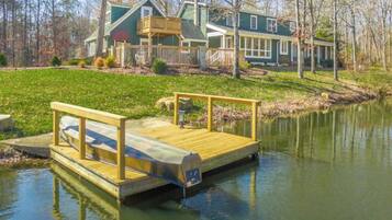 A wooden dock extending into a calm body of water, with a house in the background.