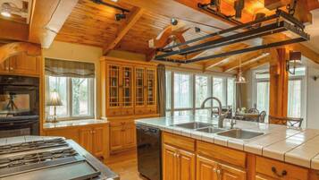 A kitchen with wooden cabinets, a stove, and a large island with a sink.
