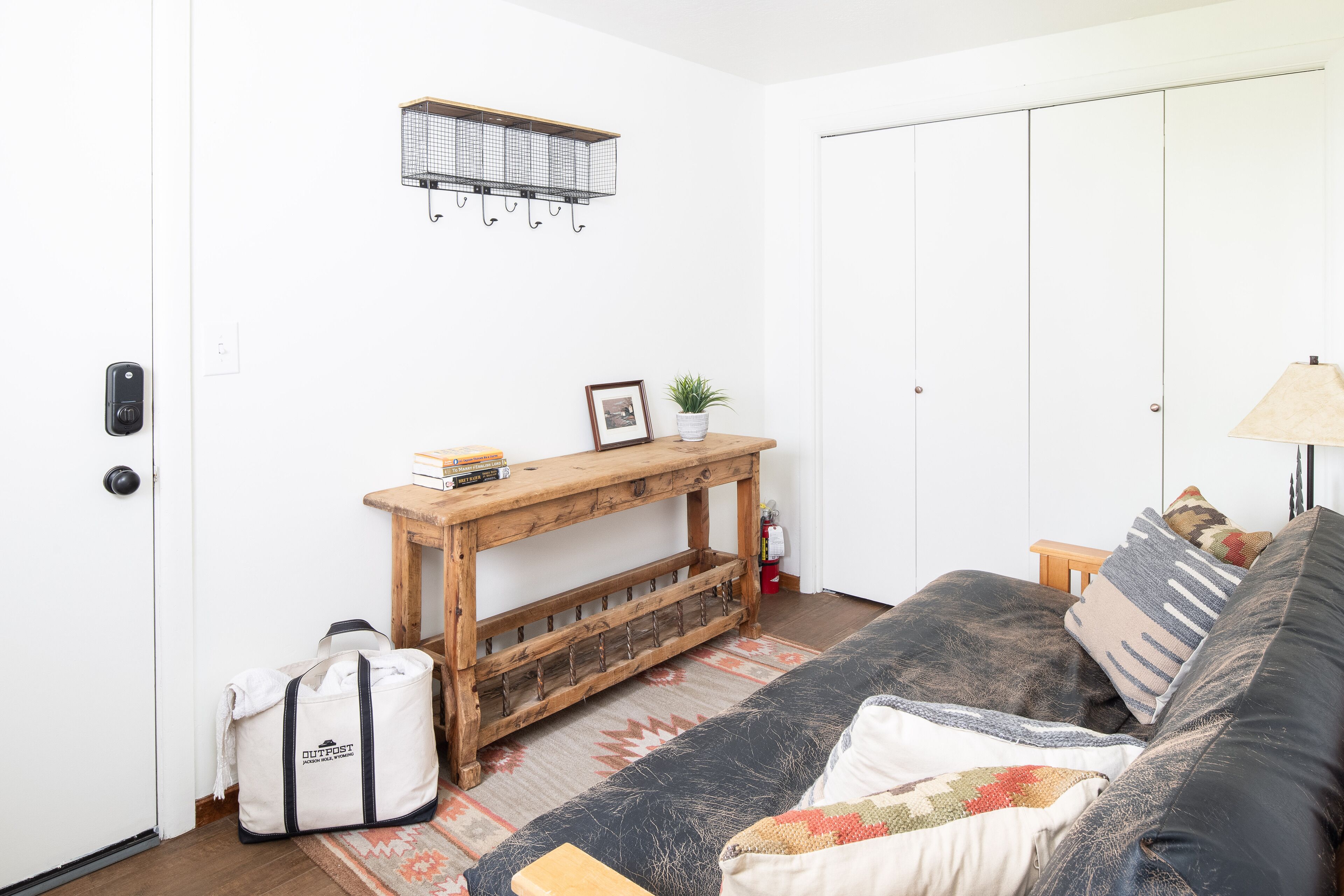 A living room with a sofa, a wooden console table, a hanging light fixture, and a door with a key lock.