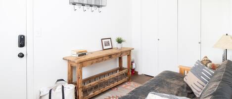 A living room with a sofa, a wooden console table, a hanging light fixture, and a door with a key lock.