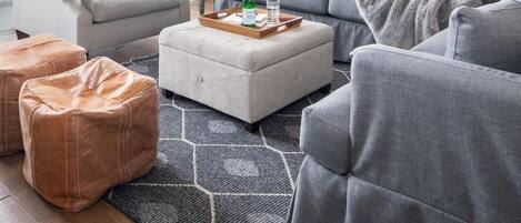 Un salon moderne avec un ventilateur de plafond, des canapés gris, une table basse et une grande fenêtre.