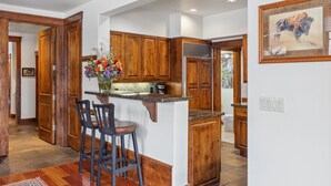 A kitchen with wooden cabinets, a granite countertop, and a bar stool.
