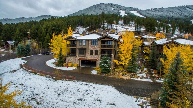 A lodge with a stone facade, multiple stories, and a covered parking area.