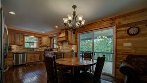 A wooden interior with a dining table and chairs, a chandelier, and a view through a sliding glass door. - LAKEFRONT, PONTOON BOAT, HOT TUB, FIREPIT, Fireplace . Wide lake Mountain View  (Blairsville)