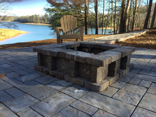 A fire pit with a wooden Adirondack chair in a park setting. - LAKEFRONT, PONTOON BOAT, HOT TUB, FIREPIT, Fireplace . Wide lake Mountain View (Blairsville)