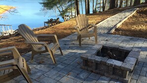 An outdoor seating area with Adirondack chairs and a stone fire pit. - LAKEFRONT, PONTOON BOAT, HOT TUB, FIREPIT, Fireplace . Wide lake Mountain View  (Blairsville)