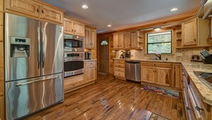 A modern kitchen with wooden cabinets, stainless steel appliances, and a large window. - LAKEFRONT, PONTOON BOAT, HOT TUB, FIREPIT, Fireplace . Wide lake Mountain View  (Blairsville)