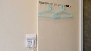 A wall-mounted coat rack with two hangers and a white electrical outlet with a coiled cord. - HK Mingdu Hostel (Kowloon)