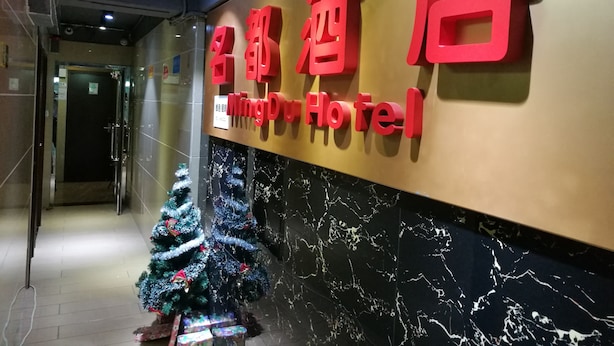 A hotel entrance with a Christmas tree and a sign in both Chinese and English. - HK Mingdu Hostel (Kowloon)