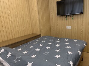 A room with a bed, a TV mounted on the wall, and a wooden shelf. - HK Mingdu Hostel (Kowloon)