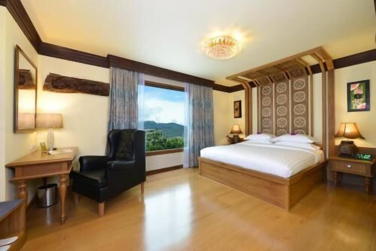 Een hotelkamer met een groot bed, een stoel, een bureau en uitzicht op de omgeving.