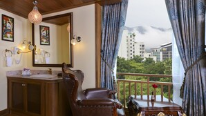 Une salle de bain avec un meuble-lavabo en bois, un grand miroir et une vue sur un balcon doté d’une balustrade et d’une table.