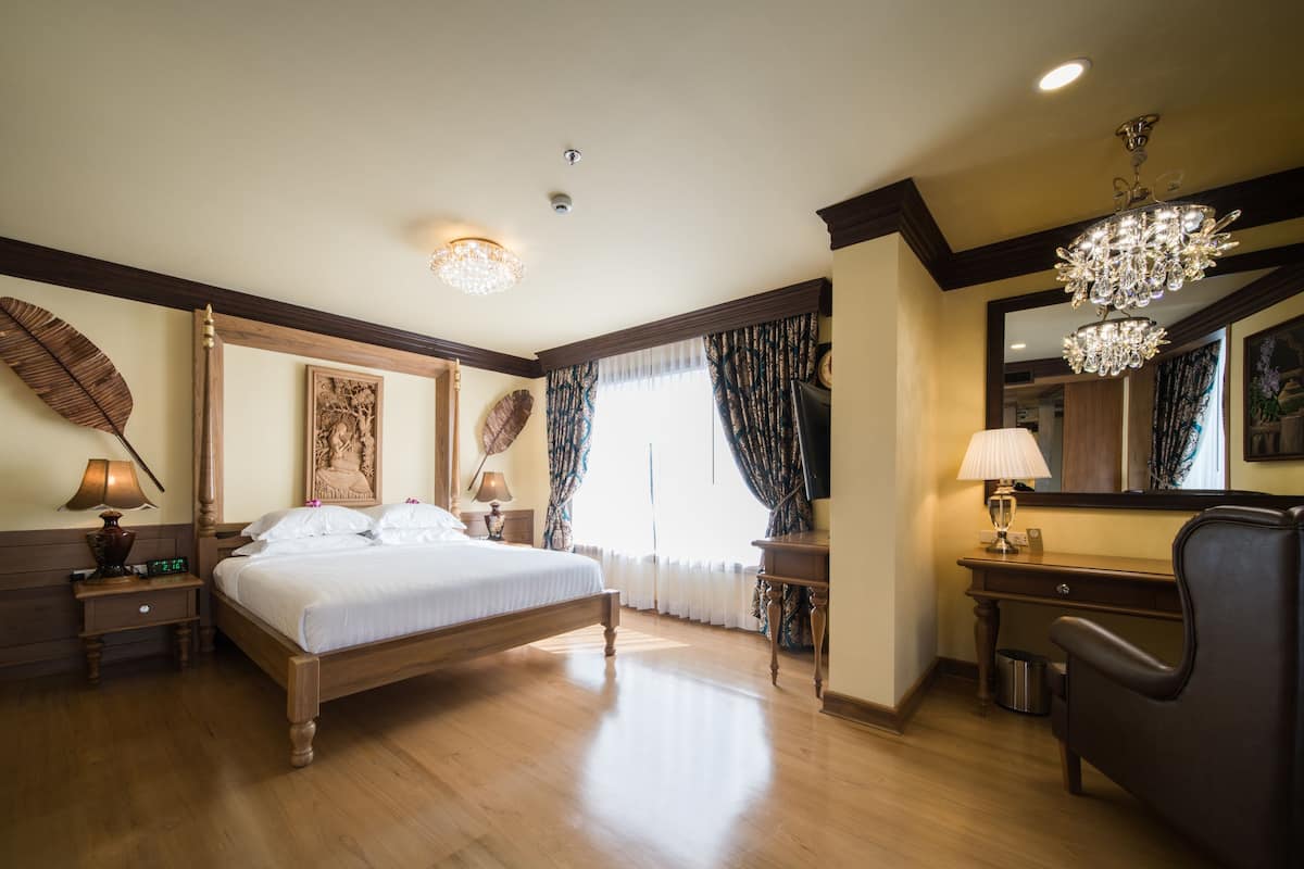 A spacious bedroom with a large bed, wooden headboard, and a chandelier.