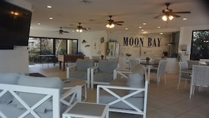 A spacious living area with white furniture, ceiling fans, and a wall with "MOON BAY" written on it. - Another Day in Paradise           Best Waterfront and Poolside  Views. (Key Largo)