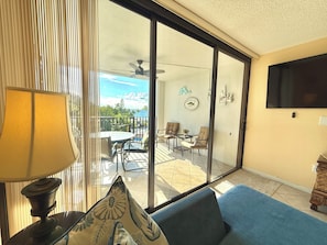 A room with a view of the ocean, a ceiling fan, a table with chairs, and a TV mounted on the wall. - Another Day in Paradise           Best Waterfront and Poolside  Views. (Key Largo)