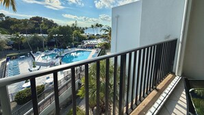 A pool area with lounge chairs and umbrellas, surrounded by palm trees and a clear sky. - Another Day in Paradise           Best Waterfront and Poolside  Views. (Key Largo)