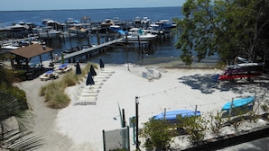 A marina with boats docked, a pier, and a sandy beach area with sun loungers and umbrellas. - Another Day in Paradise           Best Waterfront and Poolside  Views. (Key Largo)