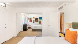 A hotel room with a bed, a desk, a chair, and a wall with framed pictures. - Desert Modern by Jack Meiselman with Pool/Spa (Palm Springs)