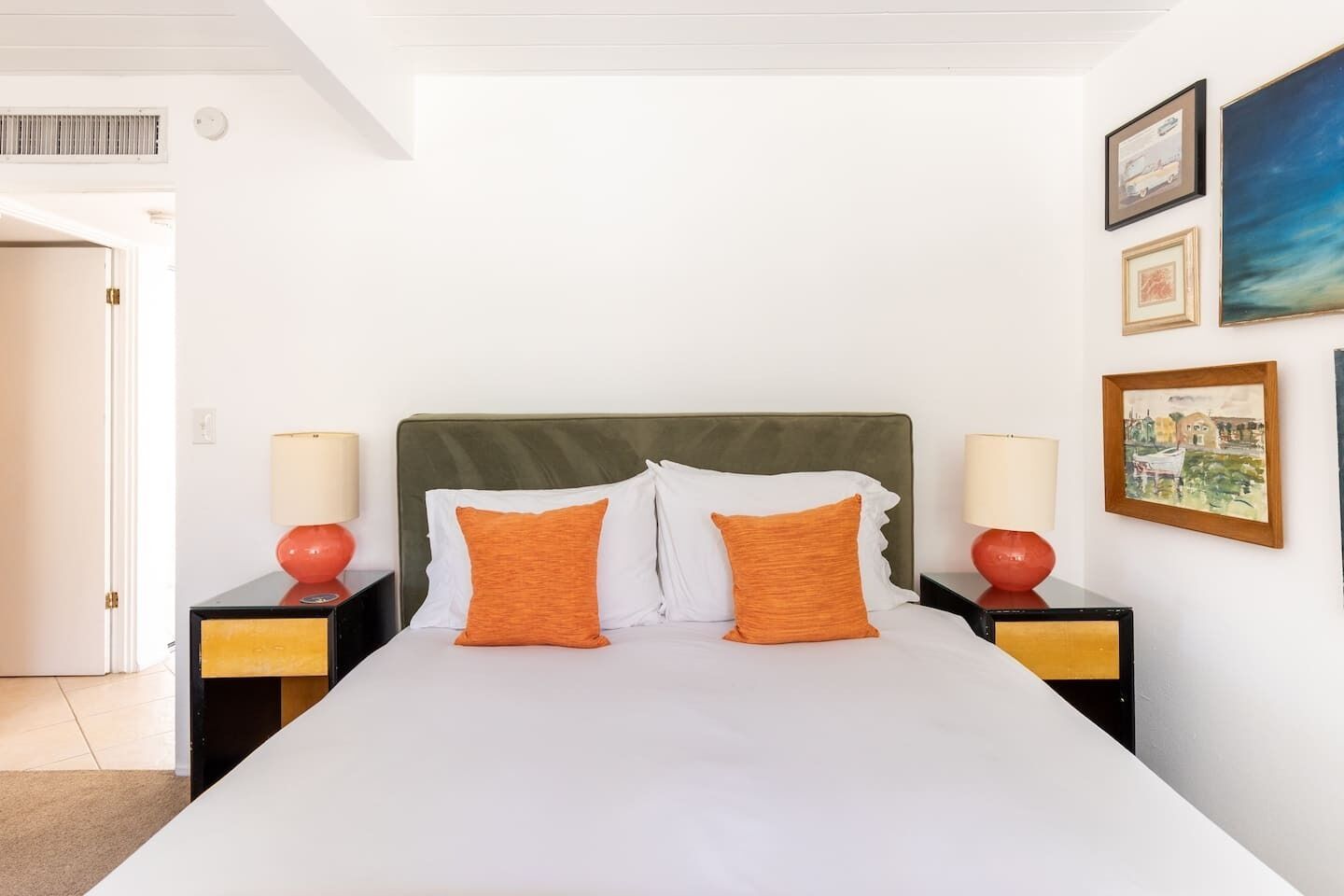 Ein Hotelzimmer mit einem Bett, zwei Nachttischen, zwei Lampen und drei gerahmten Bildern an der Wand.