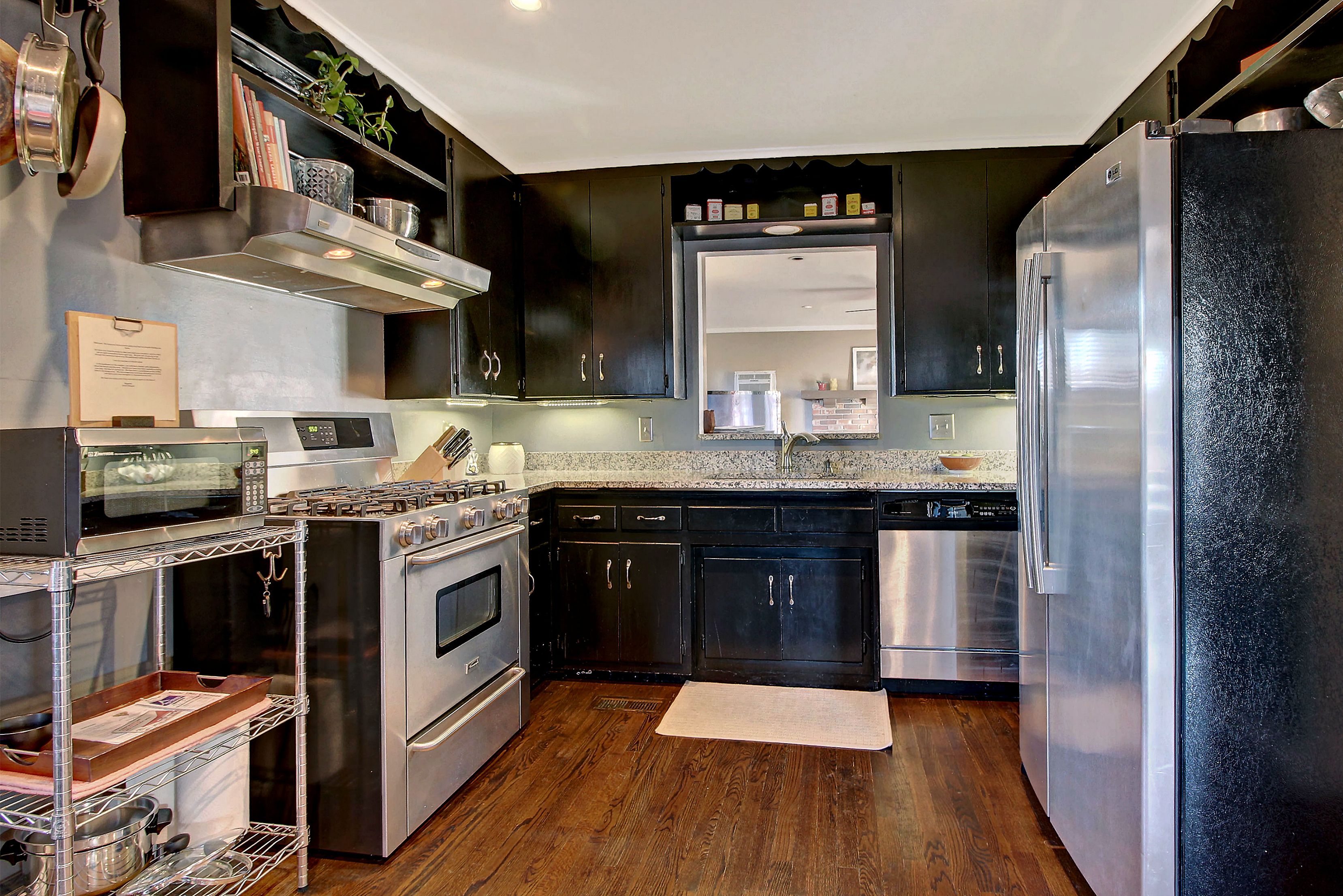 Una cocina moderna con electrodomésticos de acero inoxidable, armarios oscuros y piso de madera.