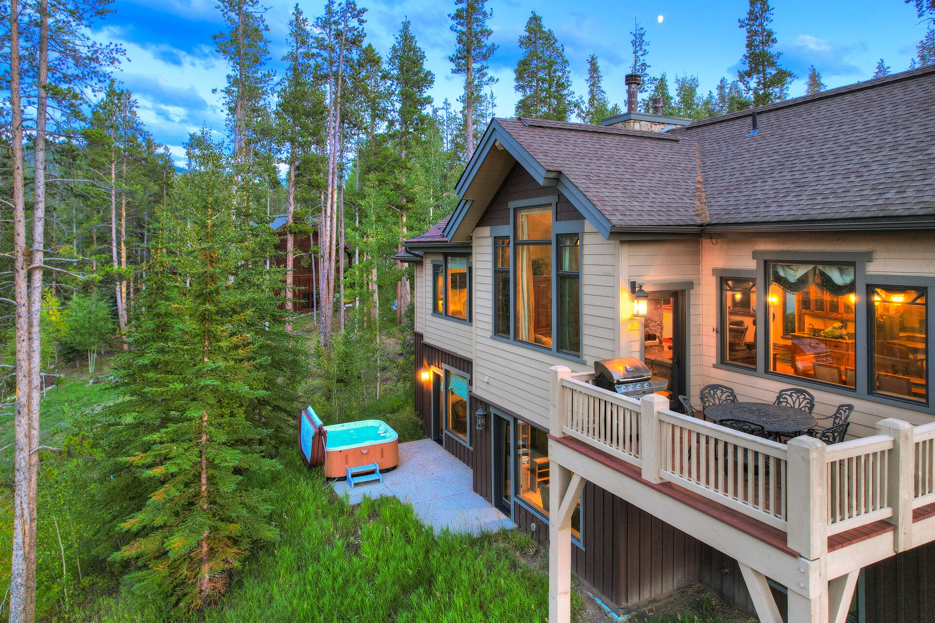 Une cabane à deux étages dotée d’une terrasse, entourée d’une forêt dense.